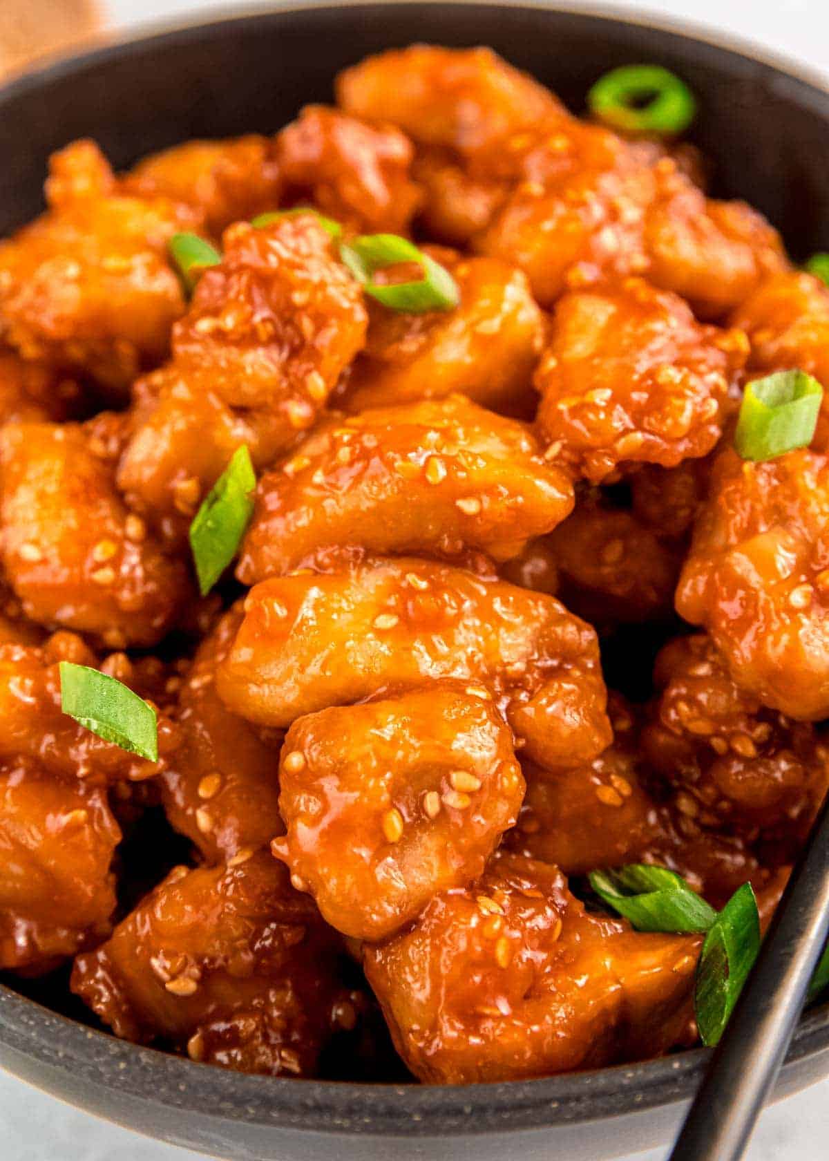 closeup of honey sesame chicken with sesame seeds and chopped green onions