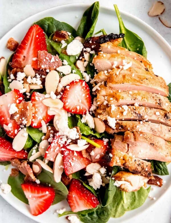 overhead image of strawberry spinach salad on a white plate