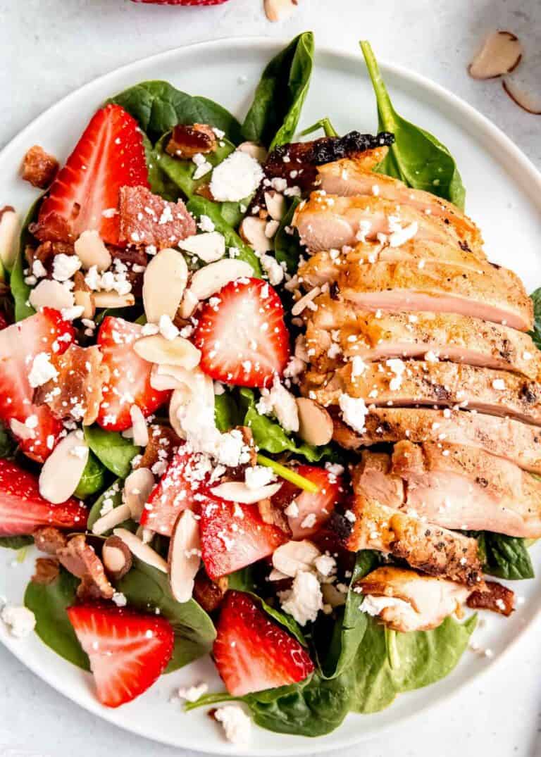 overhead image of strawberry spinach salad on a white plate