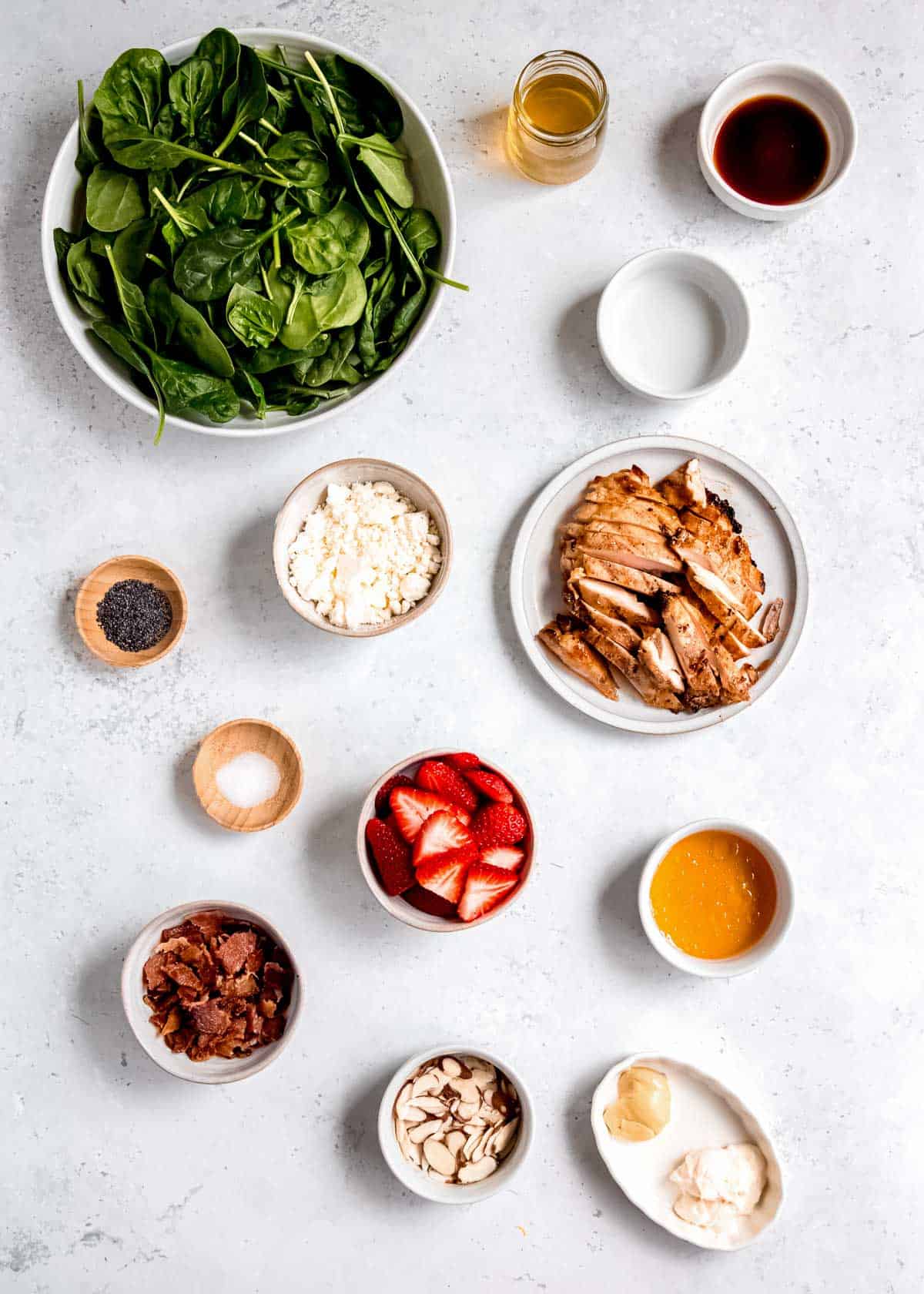 strawberry spinach salad ingredients separated on a white table