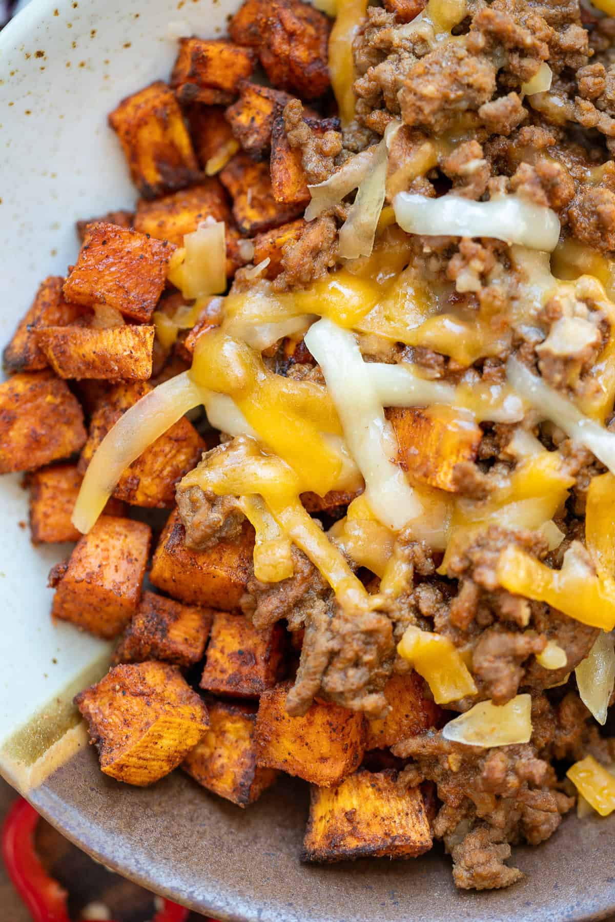 a very closeup shot of sweet potatoes, taco meat and cheese in a bowl