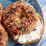 an overhead shot of a toasted everything bagel on a blue plate