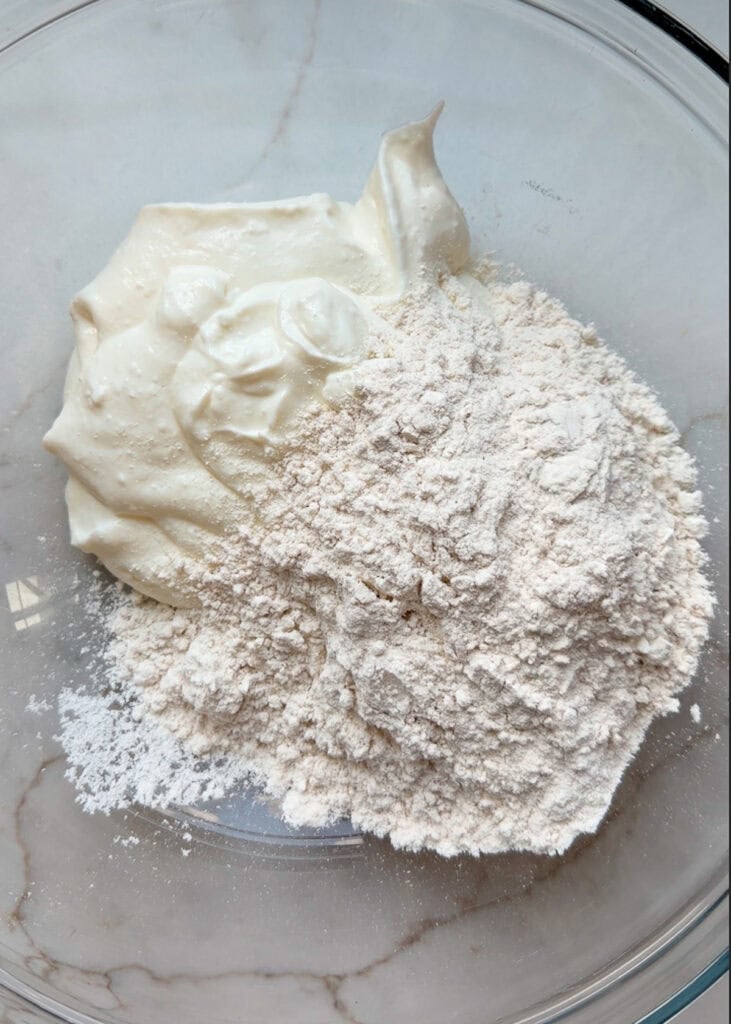 ingredients in a glass mixing bowl for everything bagels