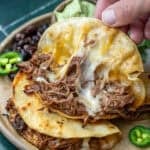 a closeup shot of a shredded beef tacos on a brown plate