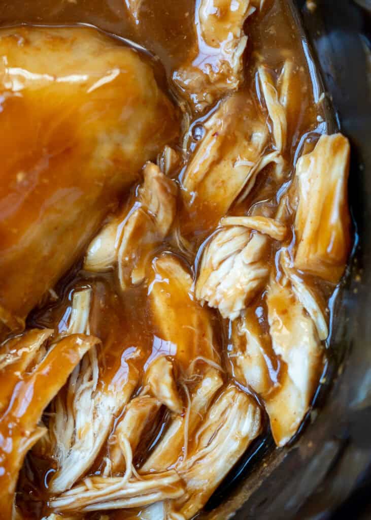 a close up shot of shredded chicken in a slow cooker