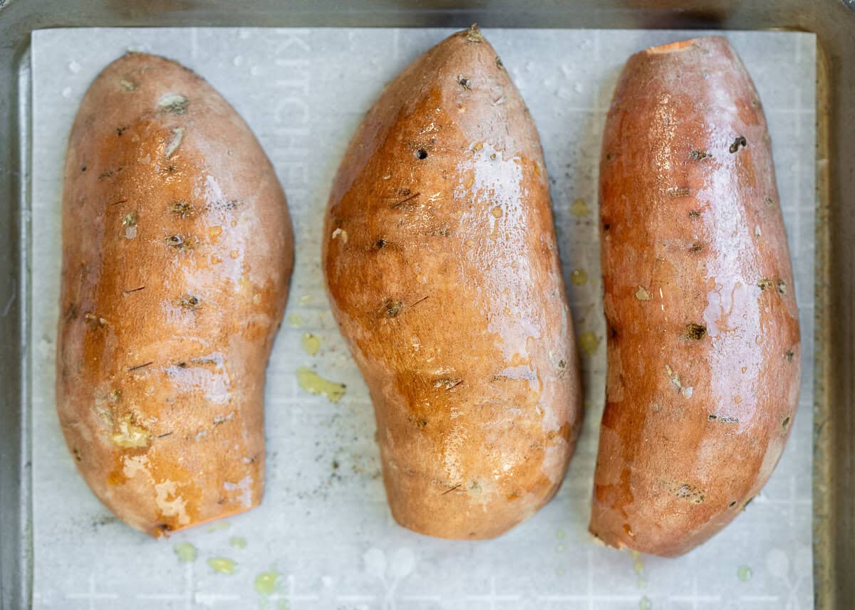 overhead image of sweet potatoes on cooking sheet after being coated with oil
