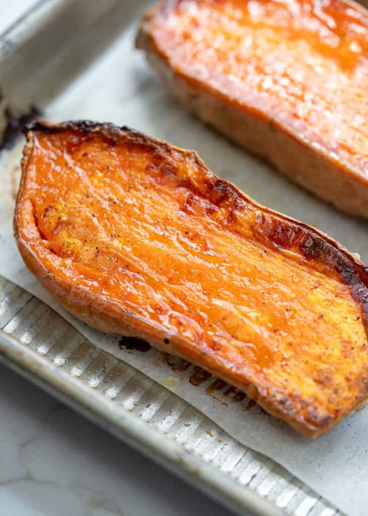 a close up shot of caramelized sweet potatoes on a baking sheet